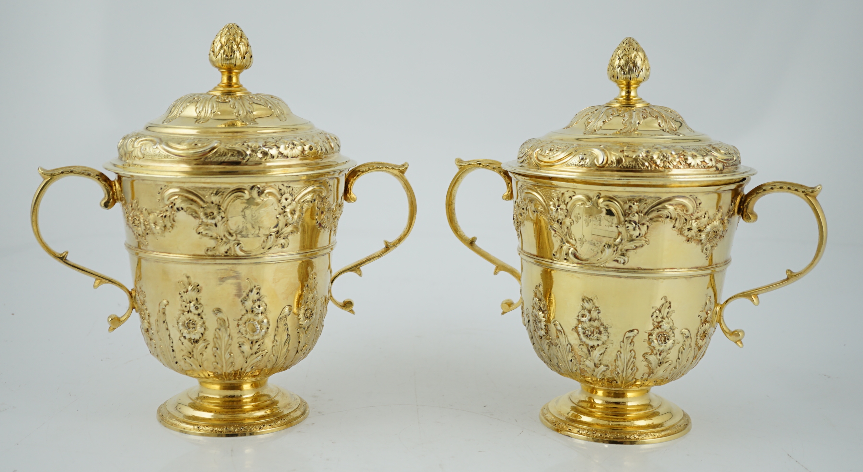 Benacre Hall, Suffolk. A good pair of George II embossed silver gilt two handled pedestal cups and covers, by Benjamin Gignac